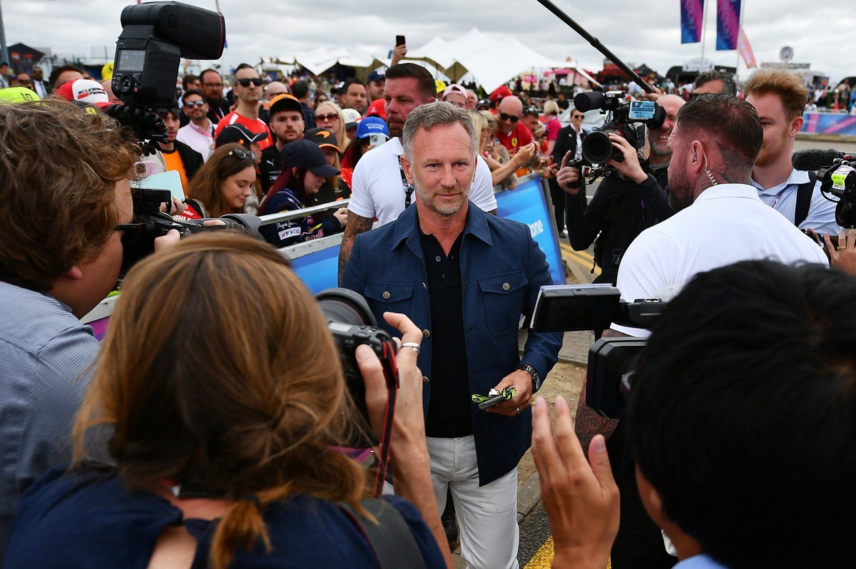 Christian Horner caminando entre una multitud de cámaras y fotógrafos a su llegada al paddock del Gran Premio de Gran Bretaña 2026