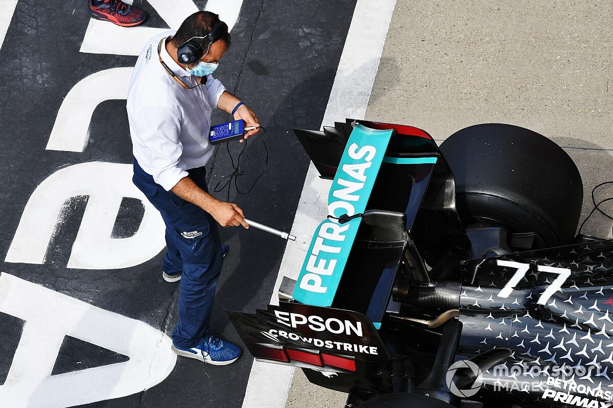 Personal técnico mide un alerón trasero durante un control reglamentario de la FIA en el paddock