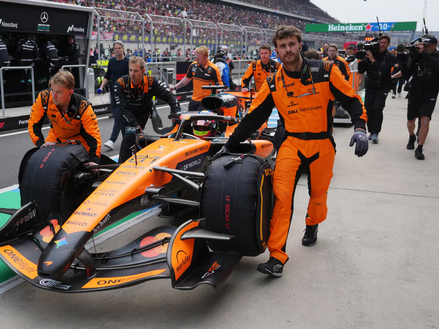 Mecánicos de McLaren empujan el monoplaza por el pit lane con neumáticos calientes antes de la salida