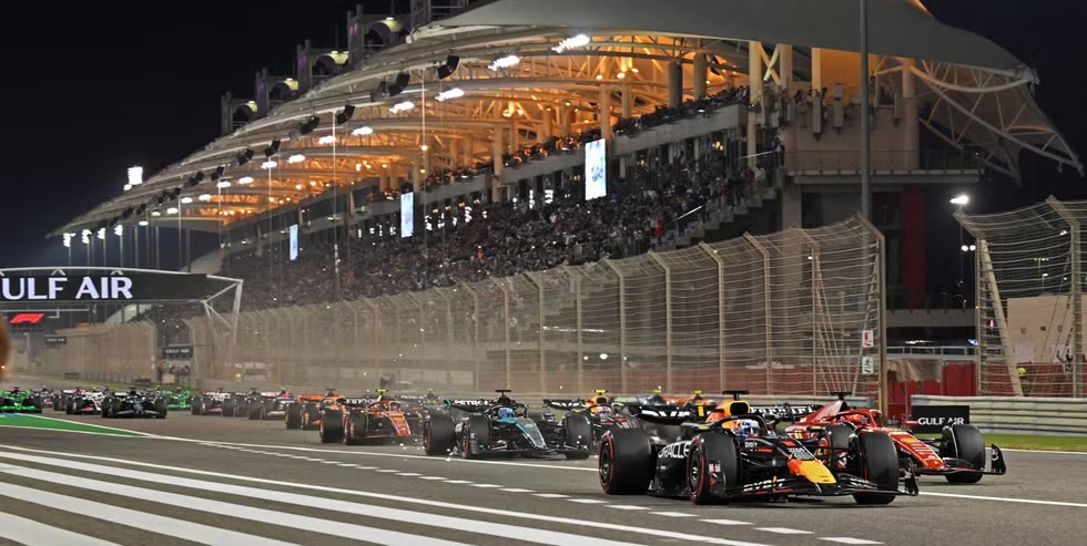 Salida nocturna del Gran Premio de Baréin con los monoplazas alineados frente a las tribunas del Bahrain International Circuit