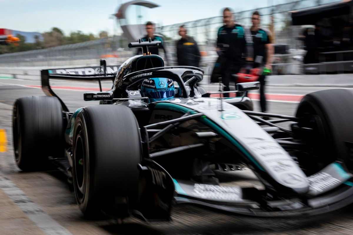 Mercedes W17 saliendo del pit lane con efecto de motion blur mientras varios mecánicos observan